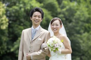 ウェディングドレスとタキシード姿で笑顔を交わす成婚カップル