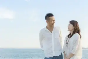 白いシャツを着たカップルが海辺で寄り添う自然な一枚
