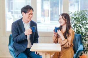 カフェで笑顔でコーヒーを飲むカップルの写真