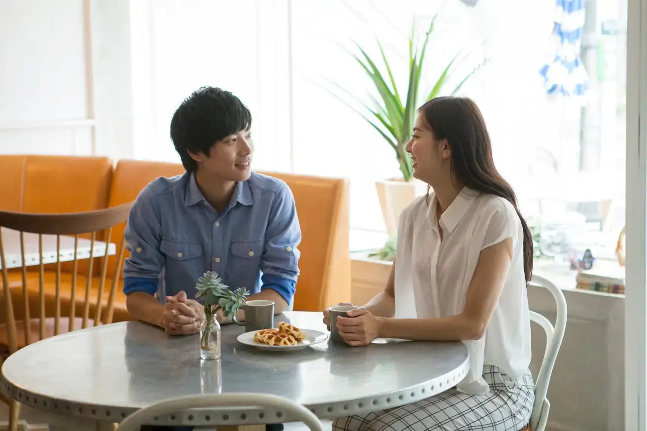 カフェで向かい合って話す男女。結婚相談の雰囲気を伝える写真。