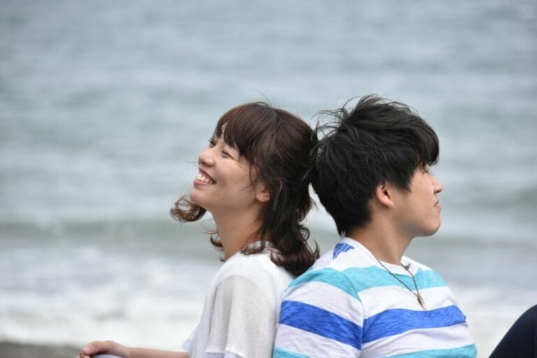 海辺で笑顔のカップルが寄り添う写真｜価値観の違いを受け入れながら関係を深めるイメージ