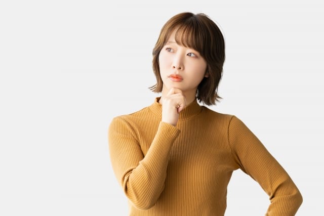 お見合いで表情がかたいと悩む女性が、真剣な表情で考え込んでいる様子