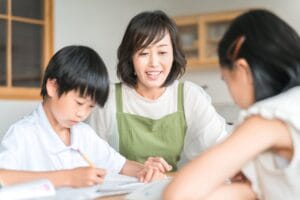 宿題を教える母親と、机に向かって勉強する子どもの様子