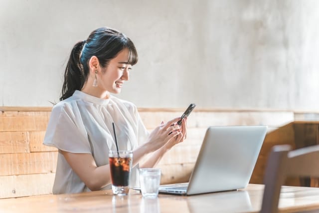 パソコンの前で笑顔の女性｜婚活で大卒以上を条件にする理由を考える