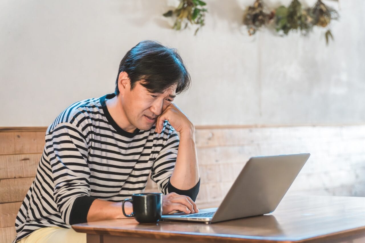 婚活がうまくいかず、パソコンを見ながら悩む岡山の30代男性