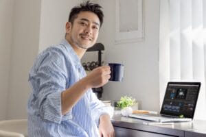 パソコンの前でコーヒーを飲みながら笑顔の男性｜婚活が前向きに進み始めた瞬間