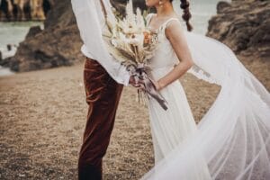 浜辺で向き合う新郎新婦のウェディングフォト。これからの人生を共に歩む結婚の象徴