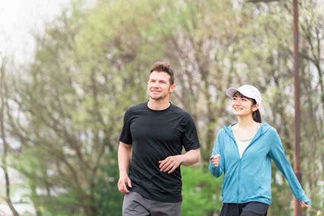 外国人男性と日本人女性が笑顔でジョギングする様子｜国籍を越えたパートナーシップをイメージした写真