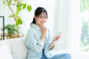 婚活で何人会うべきか悩みながらスマホを見る笑顔の女性
