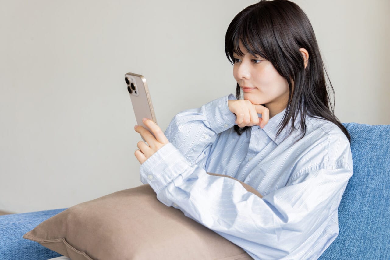 スマートフォンで結婚相談所への問い合わせを検討する女性