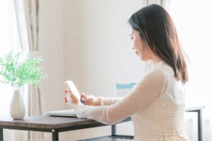 結婚相談所の料金やサポートをスマートフォンで比較検討する女性